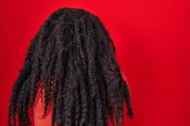 Plus size hispanic woman standing over red background standing backwards looking away with crossed arms 