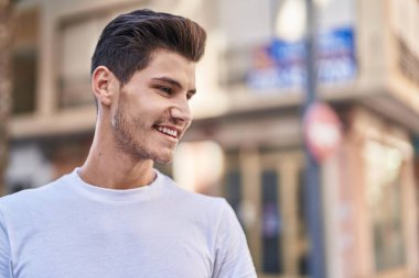 Young hispanic man smiling confident looking to the side at street