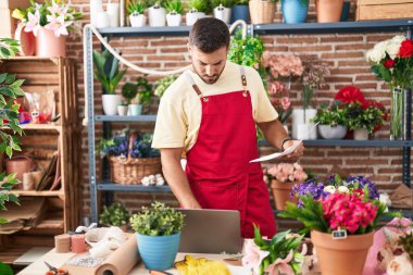 Çiçekçide dizüstü bilgisayar okuyan İspanyol bir çiçekçi.
