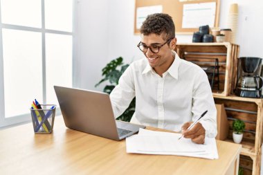 İş yerinde dizüstü bilgisayarla çalışan genç bir İspanyol.