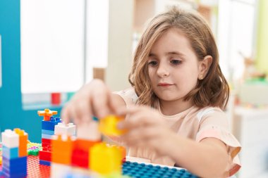Anaokulundaki masada oturan, inşaat bloklarıyla oynayan sevimli İspanyol kız.