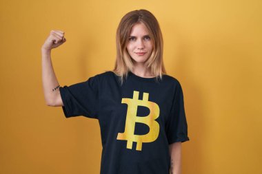 Bitcoin tişört giyen sarışın beyaz kadın güçlü kol kası gösteren, kendinden emin ve gururlu biri. 