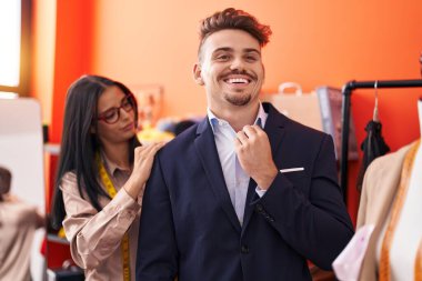 Erkek ve kadın atölyedeki müşterinin terzi ceketini dikiyor.