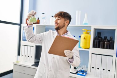 Young arab man scientist measuring liquid reading report at laboratory