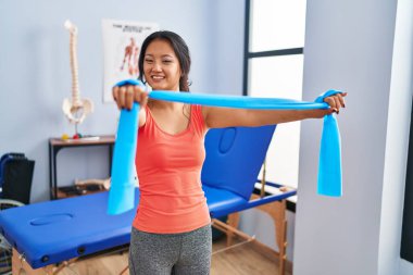 Young chinese woman patient having rehab session using elastic band at rehab clinic