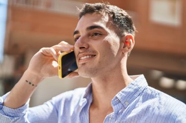 Genç İspanyol adam gülümsüyor. Kendine güveniyor. Sokakta akıllı telefondan konuşuyor.