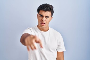 Mavi arka planda dikilen İspanyol adam kameraya kızgın ve sinirli olduğunu gösteriyor. 