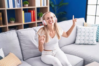 Genç sarışın kadın evde şarkı söylüyor.