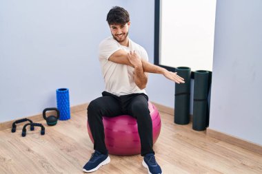 Genç İspanyol adam gülümsüyor spor merkezinde esniyor.