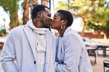 Man and woman couple standing together kissing at park
