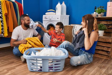 Family smiling confident playing with clothes at laundry room