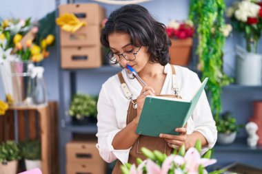 Çiçekçide defter okuyan güzel bir İspanyol kadın.