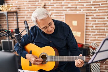 Müzik stüdyosunda gitar çalan son sınıf müzisyen.