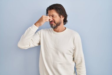 Yakışıklı orta yaşlı bir adam mavi arka planda sıradan bir süveter giyiyor. Kokuşmuş ve iğrenç bir koku alıyor. Dayanılmaz bir koku. Kötü kokuyor. 