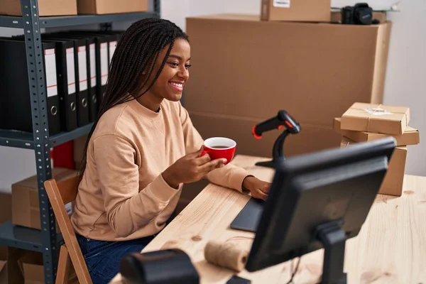 在办公室使用笔记本电脑喝咖啡的非裔美国妇女电子商务工作者 — 图库照片