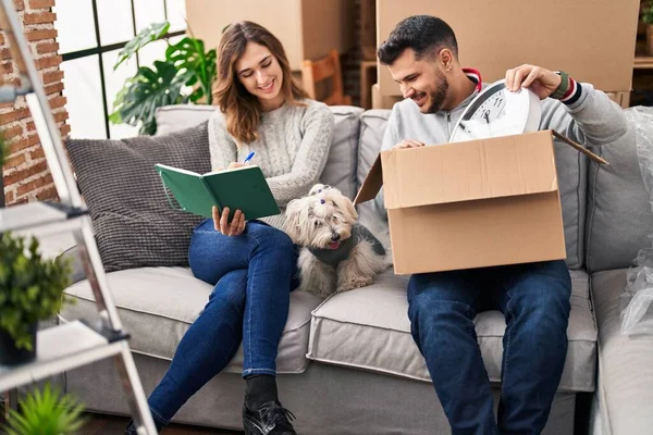 Man Woman Unpacking Box Writing Notebook Sitting Sofa Dog New – stockfoto