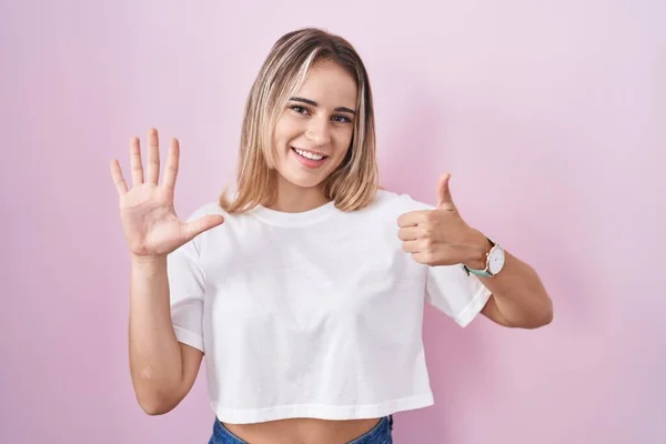 Молодая Блондинка Стоит Розовом Фоне Показывая Показывая Пальцами Номер Шесть — стоковое фото