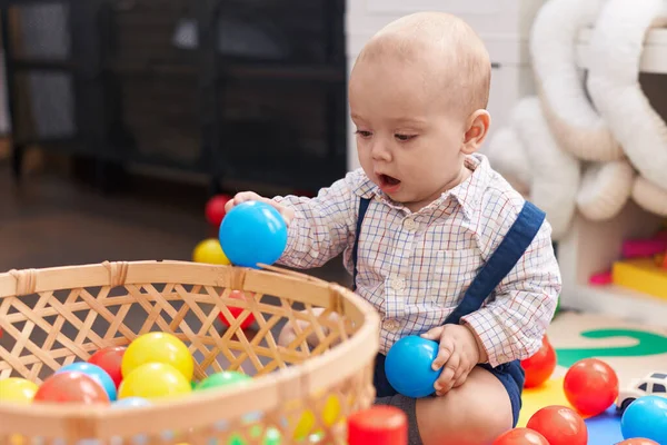 幼稚園の床に座っているボールで遊ぶ愛らしい白人の赤ちゃん — ストック写真