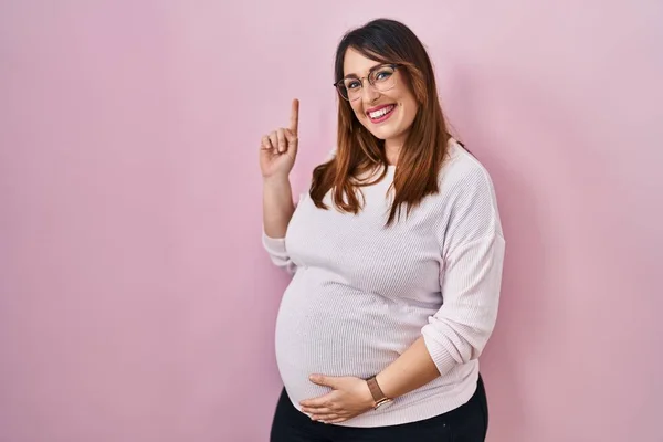 Pregnant Woman Standing Pink Background Showing Pointing Finger Number One — Stock fotografie