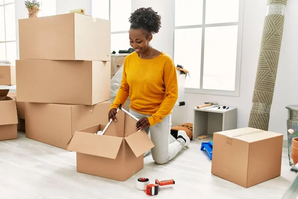 African American Woman Smiling Confident Unpacking Cardboard Box New Home — Stock Photo, Image