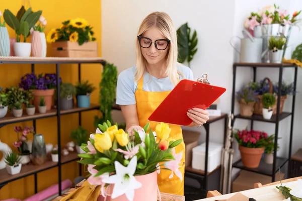 Young Blonde Woman Florist Reading Document Touching Plant Flower Shop — Stockfoto