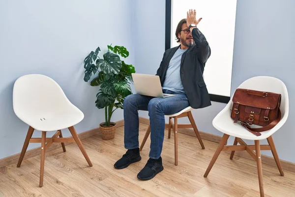 Handsome Middle Age Man Sitting Waiting Room Working Laptop Surprised — Stock Photo, Image