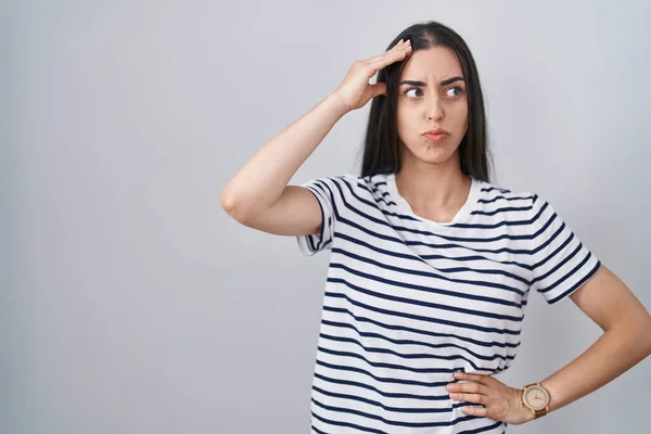 若いブルネットの女性が心配している縞模様のTシャツを着て 額に手で問題について強調し 神経と危機への不安 — ストック写真