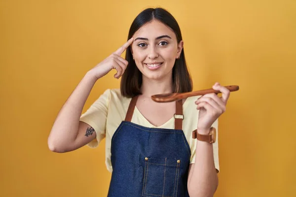 Hispanic Girl Eating Healthy Wooden Spoon Smiling Pointing Head One — Zdjęcie stockowe