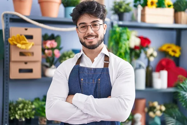 Young hispanic man florist smiling confident standing with arms crossed gesture at florist shop