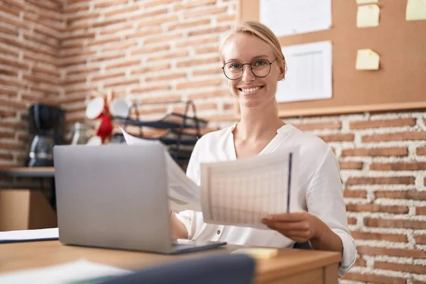 Young blonde woman business worker using laptop reading documents at office