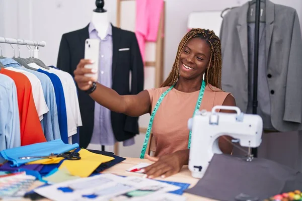 African american woman tailor smiling confident make selfie by smartphone at tailor shop