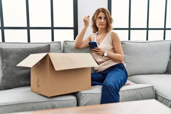 Middle Age Woman Sitting Sofa Checking Delivery Package Phone Annoyed — Stock Photo, Image