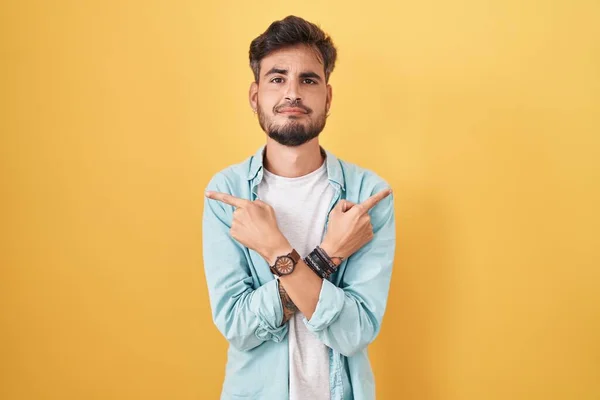 Joven Hombre Hispano Con Tatuajes Pie Sobre Fondo Amarillo Apuntando —  Fotos de Stock