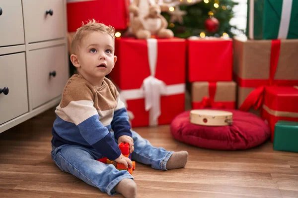 可爱的幼儿在家里拿着圣诞礼物坐在地板上玩建筑块 — 图库照片