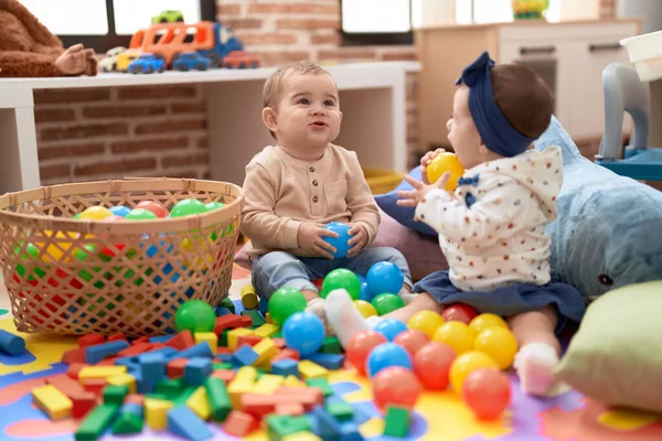 幼稚園の床に座ってボールで遊んでいる2人の幼児 — ストック写真