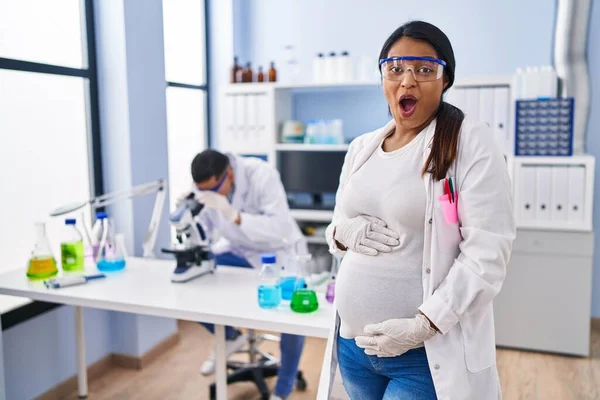 Young Hispanic Woman Expecting Baby Working Scientist Laboratory Scared Amazed — ストック写真