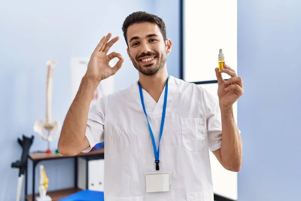 Young Hispanic Physiotherapist Man Holding Cbd Oil Pain Relief Doing — Stockfoto