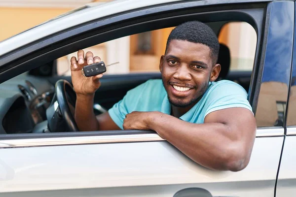 Young african american man smiling confident holding key of new car at street