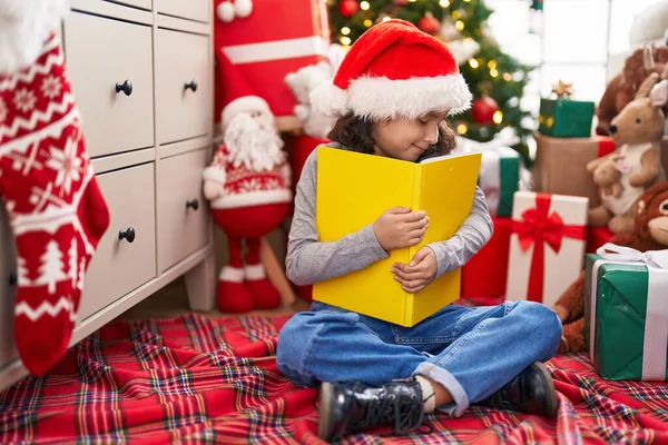 Sevimli Çinli Kız Evde Noel Ağacının Yanında Oturmuş Kitabı Kucaklıyor — Stok fotoğraf