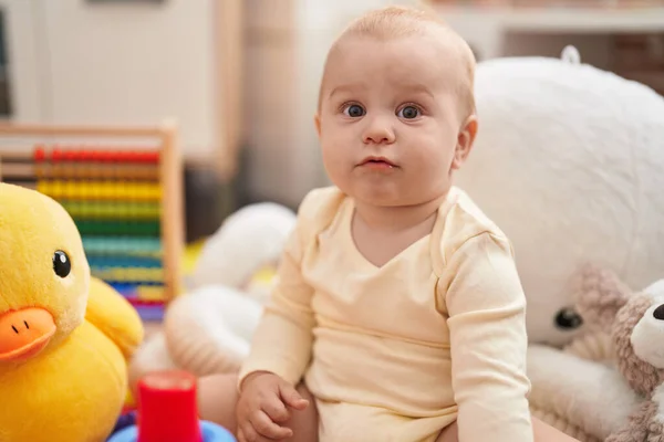 幼稚園でリラックスした表情で床に座っている愛らしい白人の赤ちゃん — ストック写真