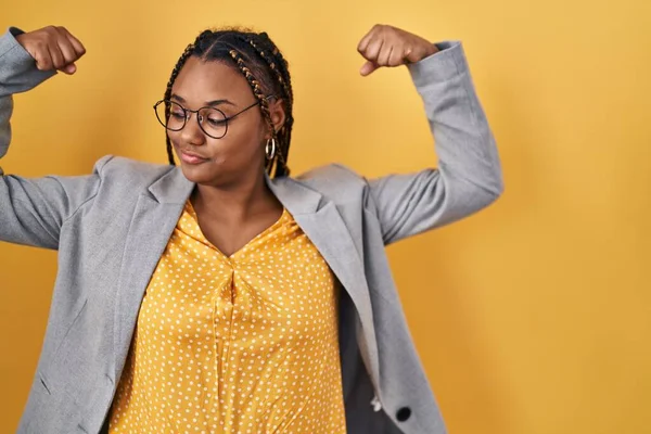 African American Woman Braids Standing Yellow Background Showing Arms Muscles — Stockfoto