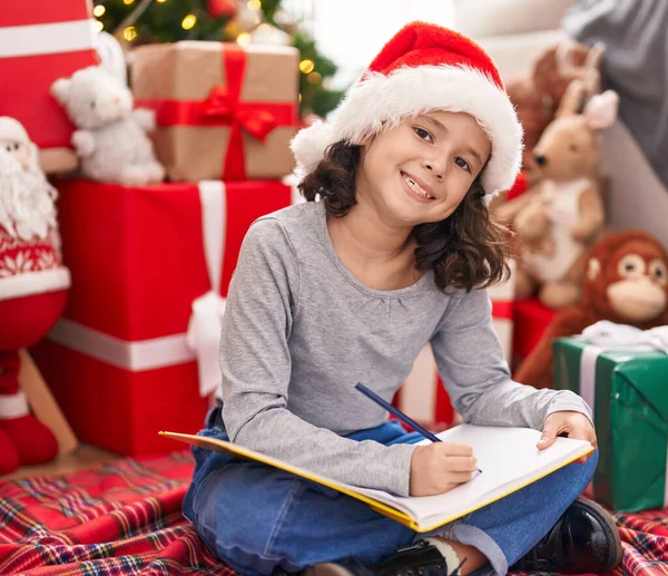 스러운 소녀는 크리스마스 바닥에 앉아서 공책에 — 스톡 사진