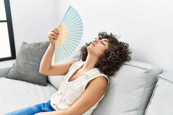 Young middle east woman desperate using hand fan at home