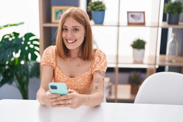 Junge Rothaarige Frau Sitzt Mit Smartphone Hause Auf Dem Tisch — Stockfoto