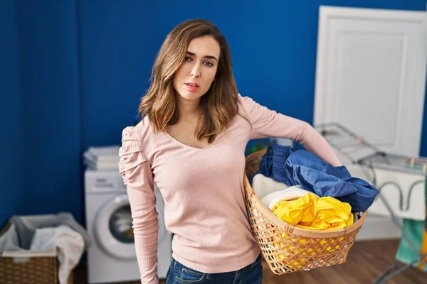 Young woman holding laundry basket looking sleepy and tired, exhausted for fatigue and hangover, lazy eyes in the morning.