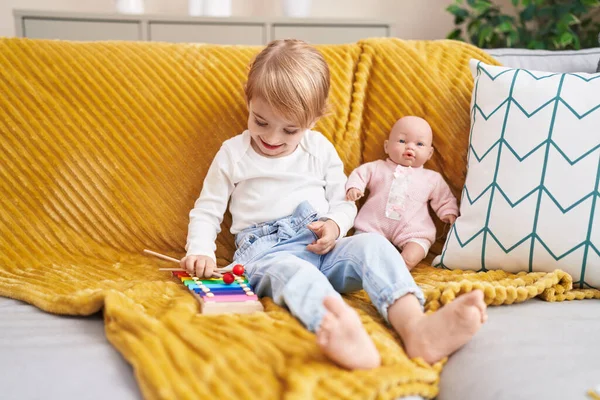 Ksilofon Çalan Sevimli Beyaz Kız Evde Oyuncak Bebekle Kanepede Oturuyor — Stok fotoğraf