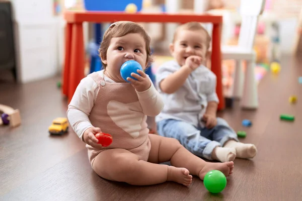 幼稚園の床に座ってボールを吸う2人の幼児 — ストック写真
