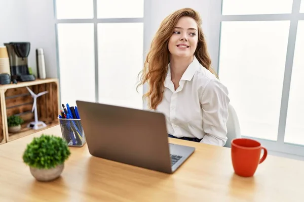 年轻的高加索女人在办公室工作时 用电脑笔记本电脑把目光移开 面带微笑 表情自然 充满自信地大笑 — 图库照片