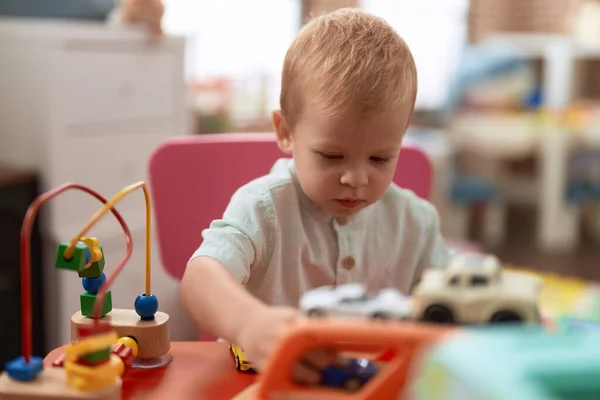 愛らしい幼児遊びとともに車のおもちゃ座っていますテーブルの上に幼稚園 — ストック写真