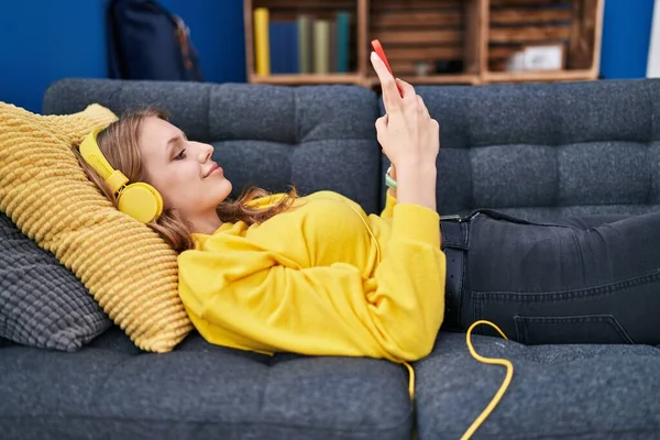Genç Sarışın Kadın Evdeki Kanepede Uzanmış Müzik Dinliyor — Stok fotoğraf